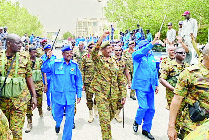 Sudan’s army chief Gen. Abdel Fattah Al-Burhan, flanked by military aides and officers, waves to people during a tour of a neighborhood in Port Sudan. (AFP)