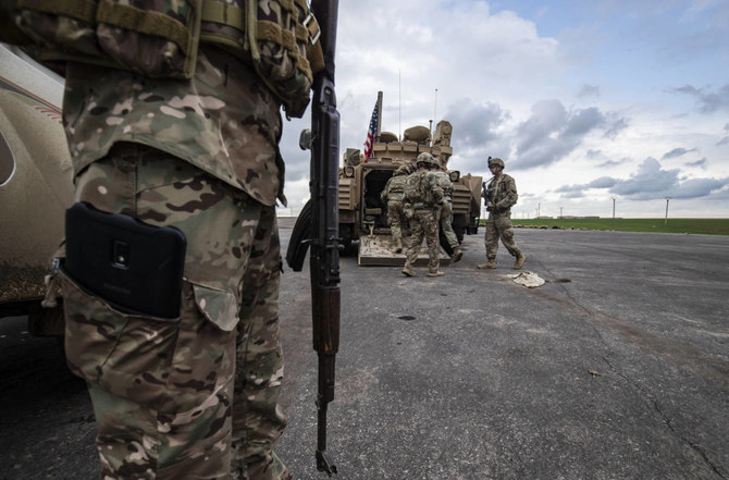 A member of the Syrian Democratic Forces (SDF) (L) and US soldiers are pictured near an armoured military vehicles are pictured on the outskirts of Rumaylan in Syria's northeastern Hasakeh province, bordering Turkey, on March 27, 2023. (AFP)