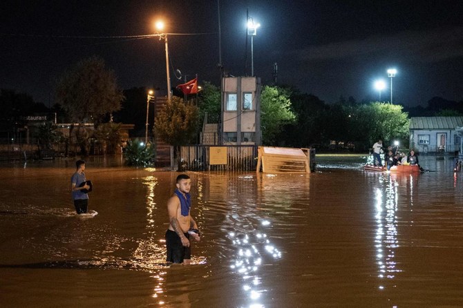 People stand in a flooded street while other are evacuated by boat in Kucukcekmece district in Istanbul. (AFP)