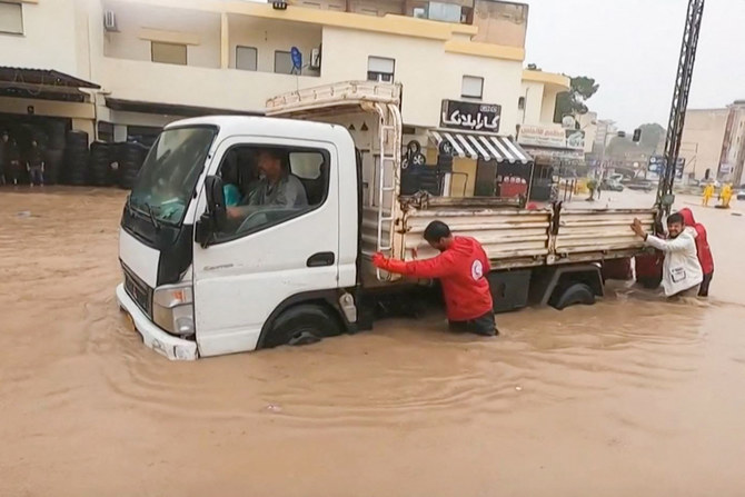 This grab from a video published on the Facebook account of the Libyan Red Crescent on September 11, 2023, shows members of their team assisting drivers whose cars are engulfed in floods in al-Bayda town in eastern Libya. (AFP)