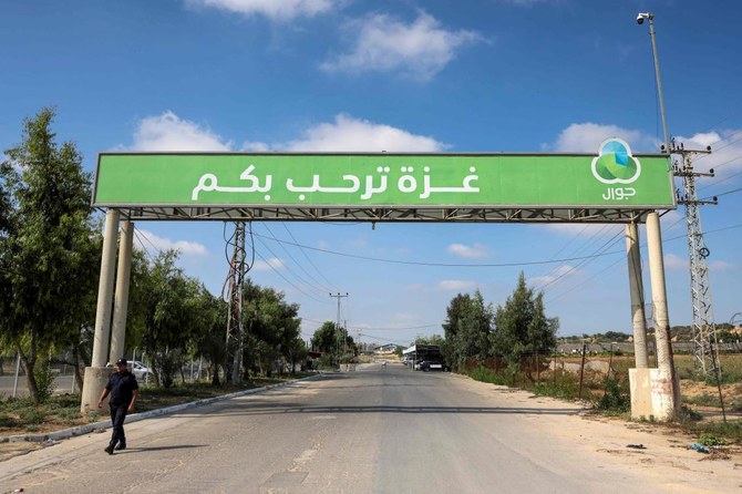 A Palestinian policeman walks beneath a giant sign reading in Arabic 