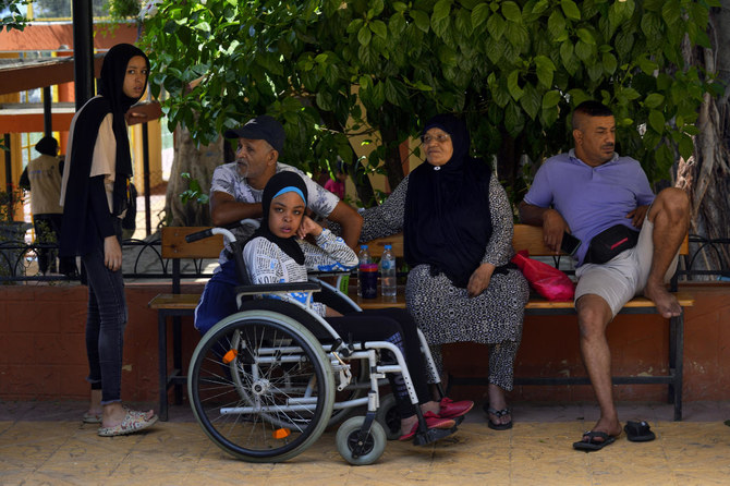 Palestinian refugee Munira Abu Aamsha, 63, second right, and other residents who fled their houses after clashes that erupted in Ein el-Hilweh refugee camp, sit at a UN-run training center in Sebline, south of Beirut on Sept. 20, 2023. (AP)