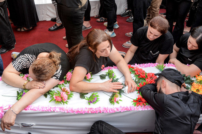 A woman mourns over a coffin during the funeral of victims who were killed when a fire ripped through a crowded wedding hall in the mainly Christian northern city of Qaraqosh, also known as Hamdaniyah, on September 27, 2023. (Zaid Al-Obeidi/AFP)