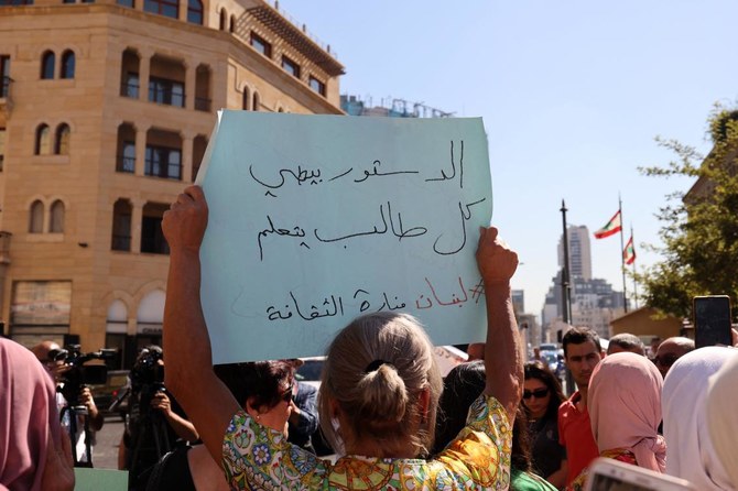 A school teacher lifts a placard during a sit in outside the Lebanese parliament in Beirut’s downtown district on Sept. 18, 2023. (AFP)