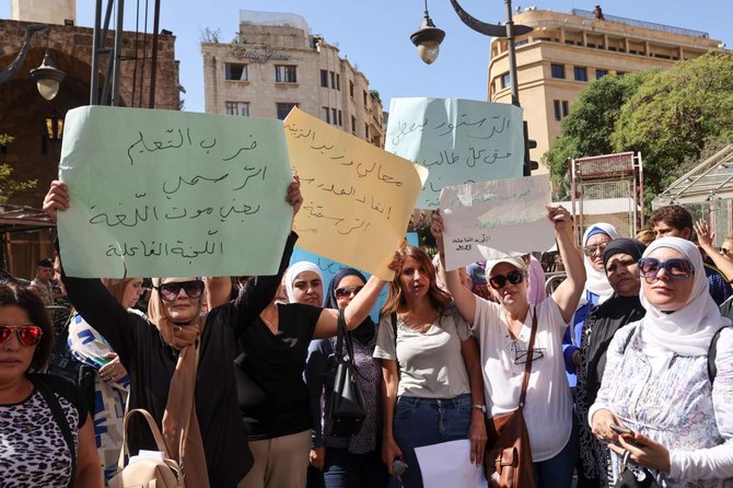 School teachers lift placards during a sit in outside the Lebanese parliament in Beirut’s downtown district on Sept. 18, 2023. (AFP)
