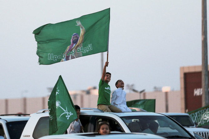 Saudi's youth hold Saudi National flag while participating in a carnival celebrating National Day in Riyadh. (Reuters)