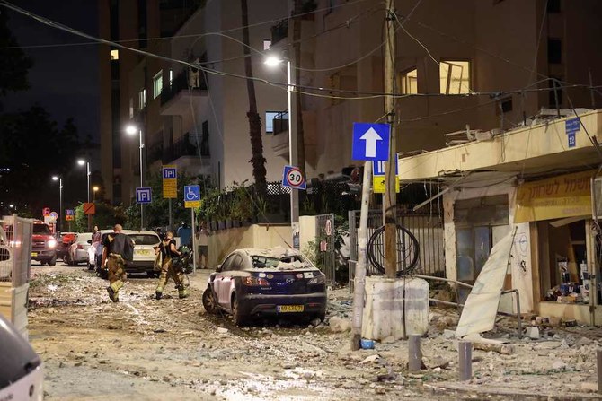 Israeli security forces walk along a street in Tel Aviv after it was hit by a rocket fired from the Gaza Strip on Oct. 7, 2023. (AFP)