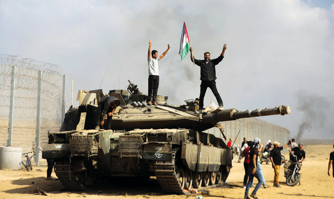 Palestinians celebrate by a destroyed Israeli tank in the Gaza Strip on Saturday. (AP)