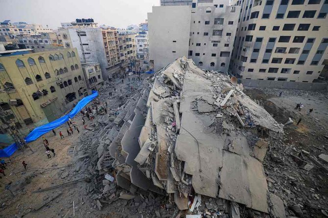 People walk around the ruins of a building destroyed in Israeli strikes in Gaza City on Oct. 8, 2023. (AFP)