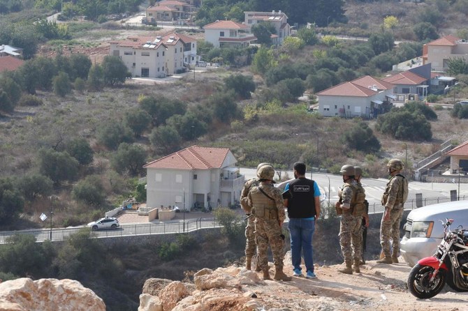 Lebanese soldiers and bystanders stand on a road overlooking the border area with the northern Israeli town of Metulla (background) on October 9, 2023.(AFP)