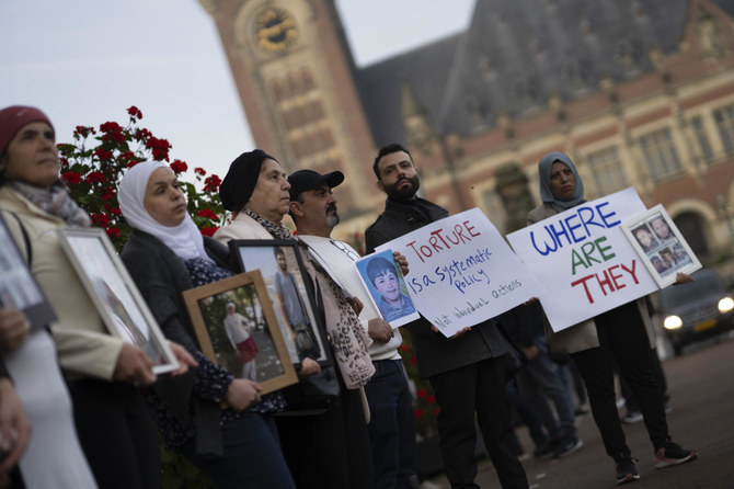 Demonstrators display pictures of people they say disappeared in Syria outside the World Court, where preliminary hearings opened in a case in which the Netherlands and Canada are suing Syria at the International Court of Justice (AP)