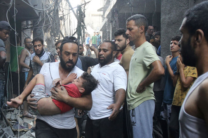 A Palestinian man rushes past rubble carrying a child in his arms, following an Israeli military strike, as raging battles between Israel and the Hamas movement continue for the sixth consecutive day in Gaza (AFP)