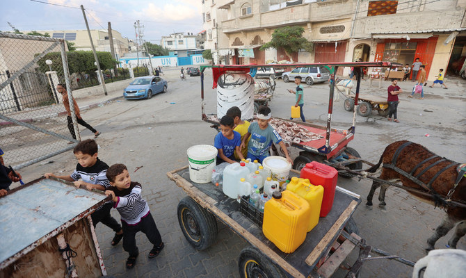 Children collect water in Khan Younis in the southern Gaza Strip on Saturday. Drinking water was in short supply amid an unrelenting bombardment. (Reuters)