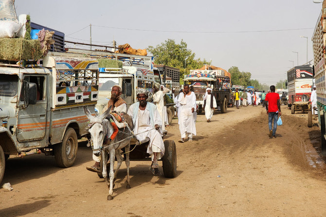 Sudanese refugees move past trucks in Shendi, 190 kilometers from Khartoum, on September 21, 2023, as fighting between the armed forces and paramilitary RSF continues. (AFP)