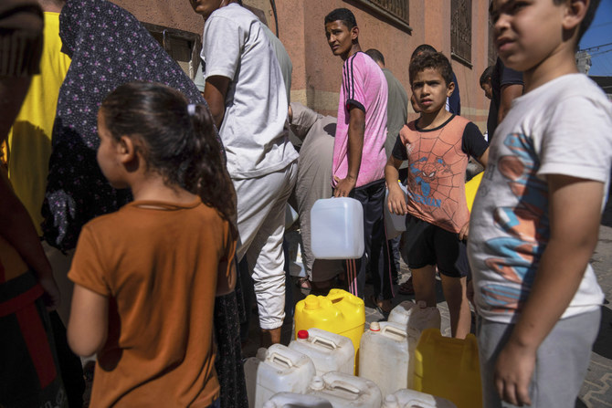 Palestinians collect water from a water tap, amid drinking water shortages, in Khan Younis, Gaza Strip, Sunday, Oct, 15, 2023. Israel cut off water to Gaza after a Hamas attack last week killed 1,300 people and Israel's retaliatory strikes killed more than 2,300 Palestinians. (AP)
