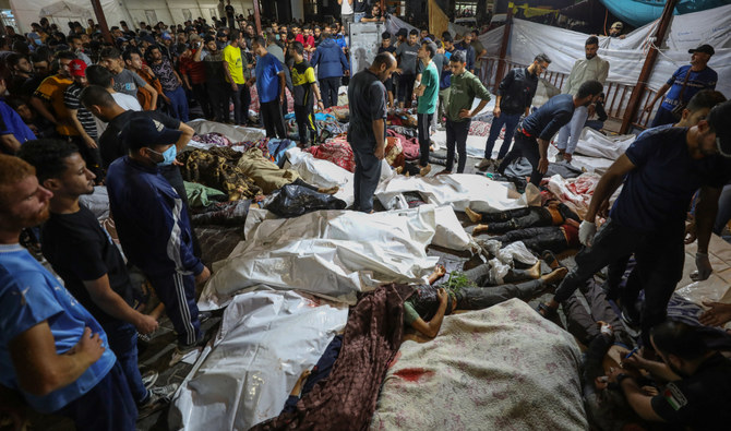 People gather around bodies of Palestinians killed in a strike on the Ahli Arab hospital in central Gaza after they were transported to Al-Shifa hospital, on October 17, 2023. (AFP)