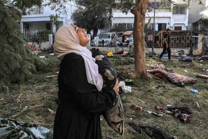 A woman cries while holding a pillow as she stands amidst debris outside the site of the Ahli Arab hospital in central Gaza on Oct. 18, 2023. (AFP)