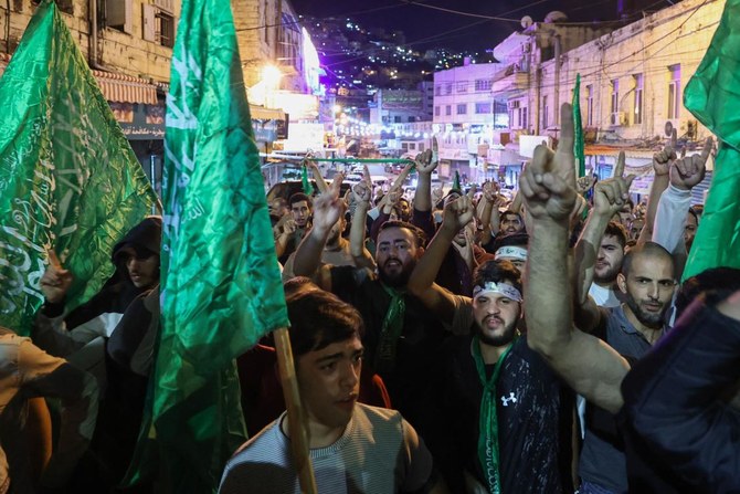 Palestinians lift Hamas movement flags as they protest in Nablus city in the occupied West Bank following an Israeli airstrike on a Gaza hospital compound killing hundreds on Oct. 17, 2023. (AFP)