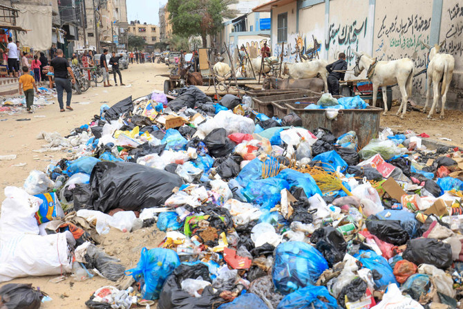 Palestinians walk amid piles of rubbish littering a street in Khan Yunis in the southern part of Gaza Strip on October 16, 2023. The relentless Israeli bombings since have flattened neighborhoods and left at least 2,670 people dead in the Gaza Strip, the majority ordinary Palestinians. (AFP)