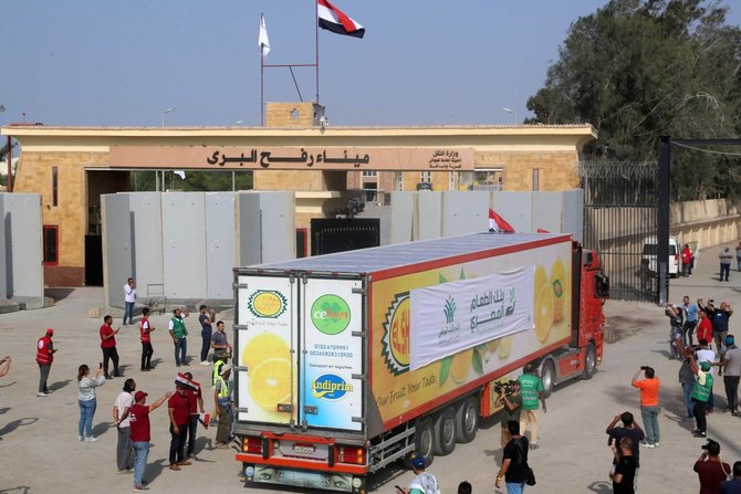 People on the Egyptian side of the Rafah border crossing watch as a convoy of lorries carrying humanitarian aid crosses to the Gaza Strip on October 22, 2023. (AFP)