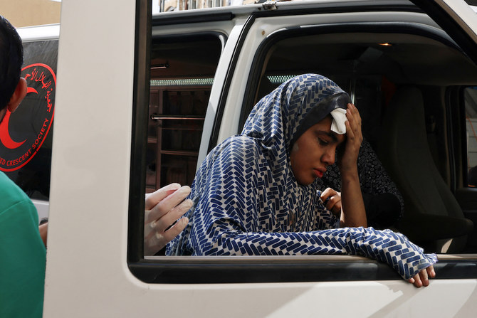 A young woman holds a handkerchief to her forehead as she leans against the window of an ambulance outside a hospital following an Israeli strike in Rafah in the southern Gaza Strip on Oct. 22, 2023. (AFP)