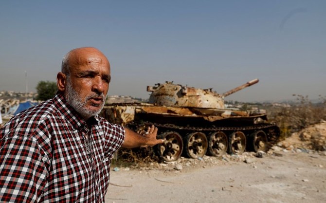 Jamil Salameh, 56, who witnessed the Israeli shelling that killed more than 100 people in 1996 stands near the wreck of an Israeli tank, Qana, Lebanon, Oct. 24, 2023. (Reuters)