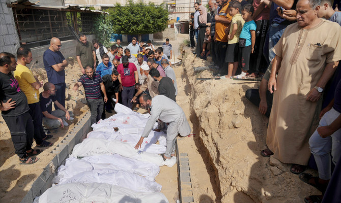 Palestinians bury the bodies of their relatives killed in Israel’s incessant bombardment in a mass grave at a cemetery in Deir Al-Balah, Gaza Strip. (AP)