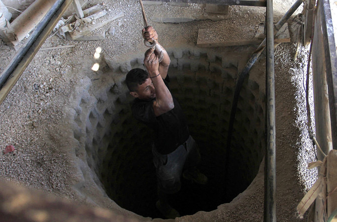 A Palestinian worker is lowered on a rope into a smuggling tunnel dug beneath the Gaza-Egypt border in the southern Gaza Strip on August 27, 2013. (AFP/File)