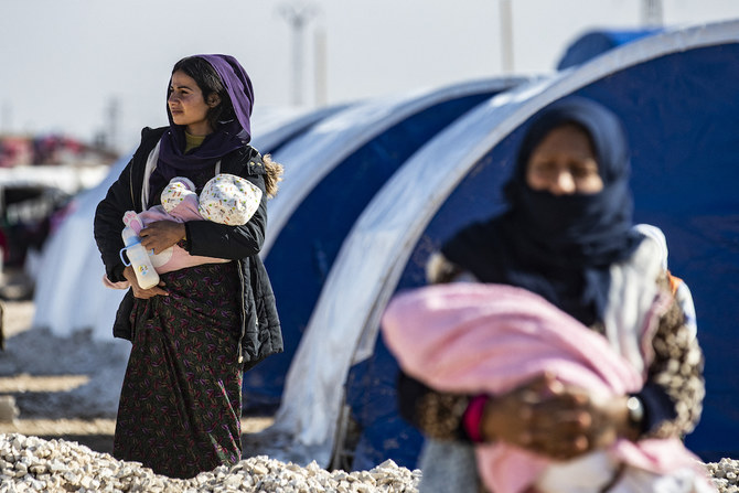 Hospitals, clinics, laboratories, pharmaceutical factories and other infrastructure for oncology care have been damaged or destroyed across Syria by years of fighting. Above, displaced Syrian women carry babies at Washukanni camp in 2019. (AFP file photo)