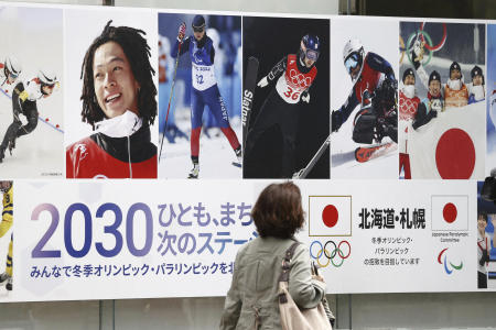 A pedestrian passes by a poster of Sapporo's bid for 2030 Winter Olympics in Sapporo, northern Japan on Oct. 6, 2023. (Kyodo News via AP)