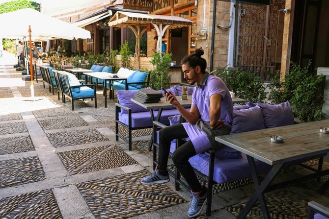 A staff waits for costumers at a restaurant in Lebanon’s coastal historical city of Byblos, on Nov. 10, 2023. (AFP)
