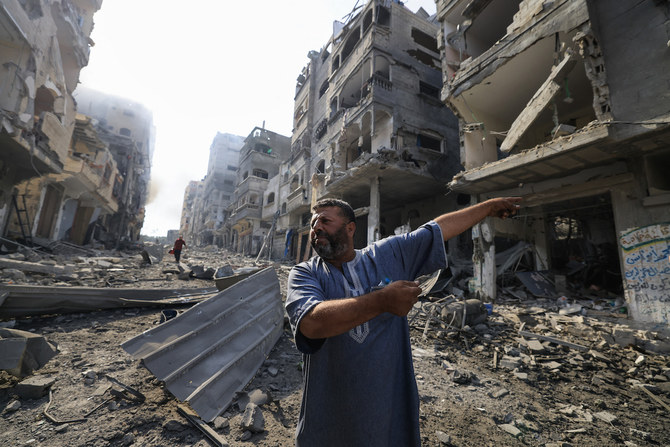 A Palestinian man points at destruction as people inspect the damage following overnight Israeli airstrikes in the Gaza Strip's Jabalia refugee camp. (File/AFP)