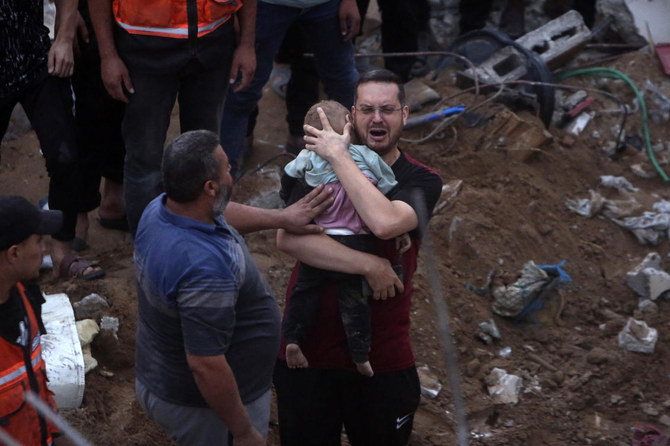 A Palestinian man cries while holding a dead child who was found under the rubble of a destroyed building following Israeli airstrikes in Nusseirat refugee camp, central Gaza. In just 25 days of war, more than 3,600 Palestinian children have been killed (AP)