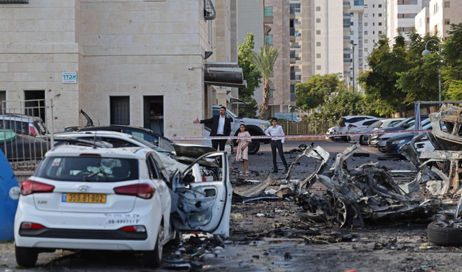Residents walk past burnt-out vehicles in Ashkelon following a rocket attack from the Gaza Strip into Israel on October 7, 2023. (AFP)