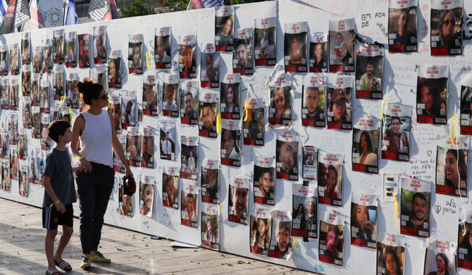 A woman with a child walks next to the wall with pictures, dedicated to hostages that are being held in Gaza after they were kidnapped from Israel by Hamas gunmen on October 7, as families and supporters of hostages hold a demonstration calling for their immediate release in Tel Aviv, Israel November 3, 2023. (REUTERS)