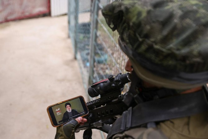 An Israeli soldier watches a televised speech by Hezbollah movement leader Hassan Nasrallah near Israel’s border with Lebanon on Nov. 11,2023, amid increasing cross-border tensions between Hezbollah and Israel. (AFP)