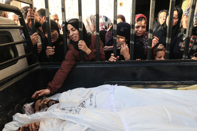 A woman reacts as she reaches out to touch the bodies of members of the Faojo family, killed in Israeli bombing on Rafah in the southern Gaza Strip, during their funeral on November 11, 2023, as battles between Israel and the Palestinian Hamas movement continue. (AFP)