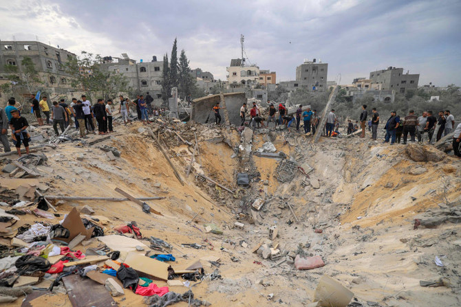 People stand over a crater following an Israeli bombardment in Khan Yunis in the southern Gaza Strip on November 12, 2023, amid the ongoing battles between Israel and the Palestinian militant group Hamas. (AFP)