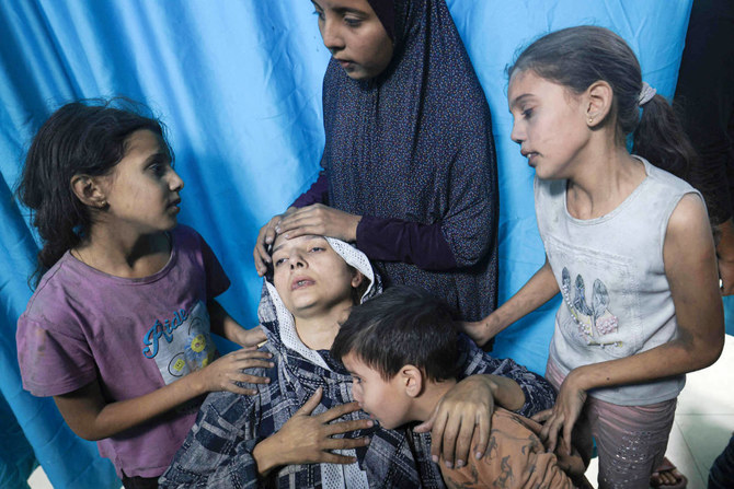 A wounded Palestinian woman from the Baraka family is surrounded by her children upon their arrival at Nasser Hospital in Khan Yunis in the southern Gaza Strip following Israeli air strikes that hit their building on November 13, 2023. (AFP)