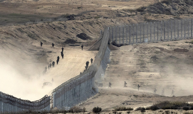 This picture taken on November 13, 2023 from a position along the border with the Gaza Strip in southern Israel shows Israeli troops crossing a barbed wire fence. (AFP/File)