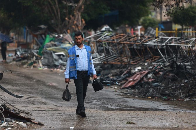 A Palestinian man wearing a United Nations blue vest walks past the debris following the Israeli bombardment of Rafah in the southern Gaza Strip on Nov. 14, 2023. (AFP)