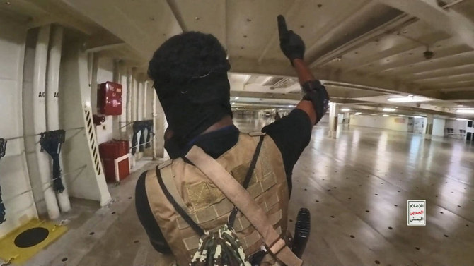 A Houthi fighter holds up a pistol in the cargo area of the Galaxy Leader cargo ship in the Red Sea in this photo released November 20, 2023. (Reuters)