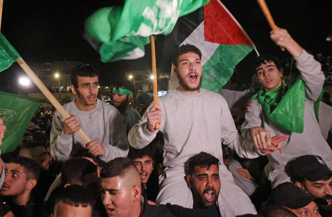 Palestinian prisoners (wearing grey jumpers) cheer after being released from the Israeli Ofer military facility in Baytunia near the city of Ramallah in the occupied West Bank in exchange for hostages freed by Hamas in Gaza, on November 24, 2023. (AFP)