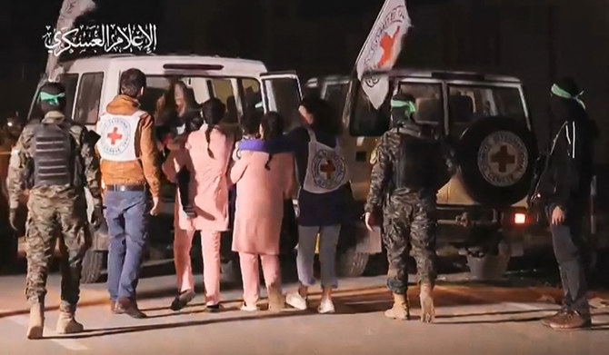 An image grab from a handout video released by the Hamas Media Office shows Hamas fighters accompanying newly released Israeli hostages (in pink) to a Red Cross vehicle, in the Gaza Strip on November 27, 2023. (AFP)