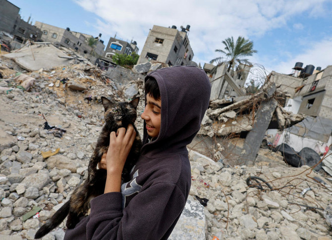 A Palestinian child holds a cat, while standing on the rubble of houses destroyed in Israeli strikes during the conflict, amid the temporary truce between Hamas and Israel, at Khan Younis refugee camp on Nov. 27, 2023. (Reuters)
