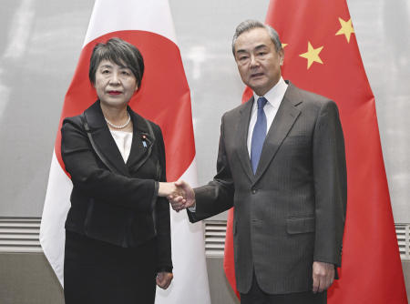 Japanese Foreign Minister Yoko Kamikawa (left) and her Chinese counterpart (Wang Yi) shake hands during their bilateral talk, in South Korea's southern port city of Busan, ahead of Sunday's three-way talks. (Kyodo News via AP)