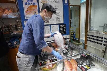 A staff member holds a flounder from Fukushima at Sakana Bacca, a seafood retailer, on Oct. 31, 2023, in Tokyo. (AP)