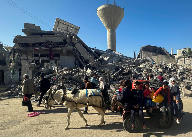 Displaced Palestinians return to their homes as they pass by a house destroyed in an Israeli strike during the conflict, amid the temporary truce between Hamas and Israel, in Khan Younis on Nov. 24, 2023. (Reuters)