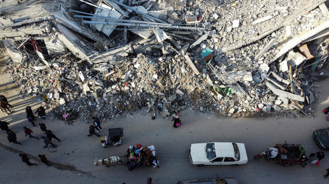 Displaced Palestinians return to their homes as they pass by a house destroyed in an Israeli strike during the conflict, amid the temporary truce between Hamas and Israel, in Khan Younis on Nov. 24, 2023. (Reuters)