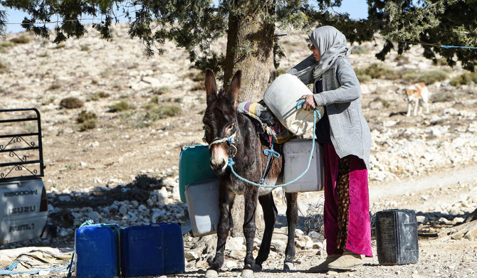 A Tunisian farmer transports water she filled up from a river on the back of a donkey in the remote village of Ouled Omar, 180 kilometres southwest of the capital Tunis, on November 28, 2023, with the north African country grappling with its worst water scarcity in years as it enters its fourth year of drought. (AFP)